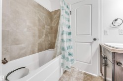 White bathtub with bronze-finish fixtures, complemented by light-toned wall tiling - 