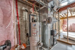 Mechanical room featuring a water heater, furnace, and exposed concrete walls - 