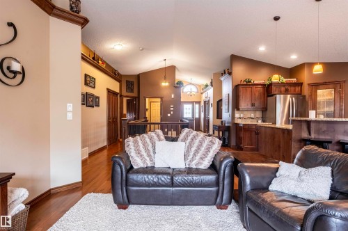 Open concept interior featuring wood-finish flooring, recessed lighting, a kitchen with wood cabinetry and stainless steel appliances, and a breakfast bar - 19 Newton Place, St. Albert, AB - Indoor Photo Showing Living Room