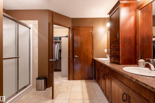 Bathroom featuring a double vanity with integrated sinks, wood cabinetry, and a patterned countertop - 19 Newton Place, St. Albert, AB - Indoor Photo Showing Bathroom