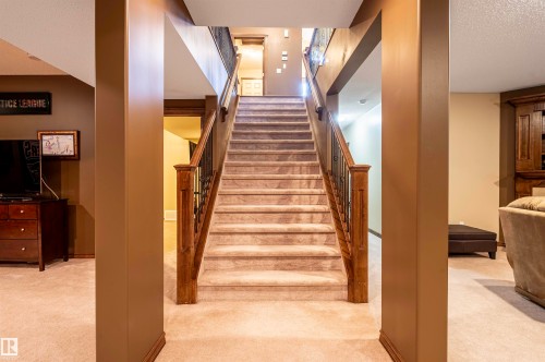 Carpeted staircase with wood newel posts and wrought iron balusters - 19 Newton Place, St. Albert, AB - Indoor Photo Showing Other Room