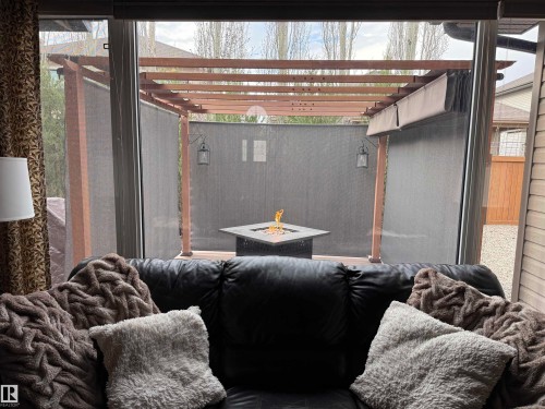 Sliding glass patio doors providing access to an outdoor living space with a wood pergola, privacy screens, and a built-in fire pit - 19 Newton Place, St. Albert, AB - Indoor