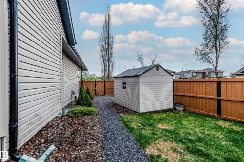 Side yard featuring a gravel path, wood chip landscaping, and a compact storage shed - 19 Newton Place, St. Albert, AB - Outdoor