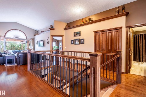 Open landing featuring wood-finish flooring, a wood and wrought-iron staircase, vaulted ceilings, and a large arched window - 19 Newton Place, St. Albert, AB - Indoor Photo Showing Other Room