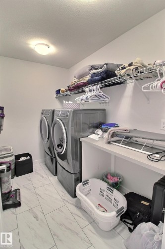 Utility room featuring light-toned flooring, built-in shelving, and a countertop - 121 Stiles Bend, Leduc, AB - Indoor Photo Showing Laundry Room