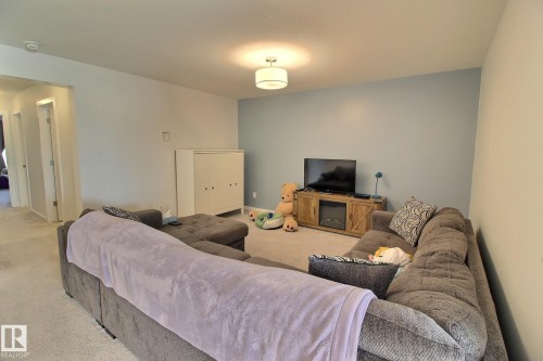 Carpeted interior space featuring light blue accent wall - 121 Stiles Bend, Leduc, AB - Indoor Photo Showing Living Room