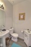 Pedestal sink with chrome faucet, toilet, and wood-finish flooring - 121 Stiles Bend, Leduc, AB  - Indoor Photo Showing Bathroom 