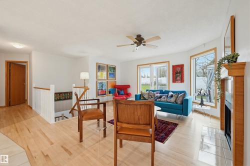 Living area featuring wood-finish flooring, white walls, and a light wood-trimmed fireplace with a tiled hearth - 317 Hollick-Kenyon Road, Edmonton, AB - Indoor
