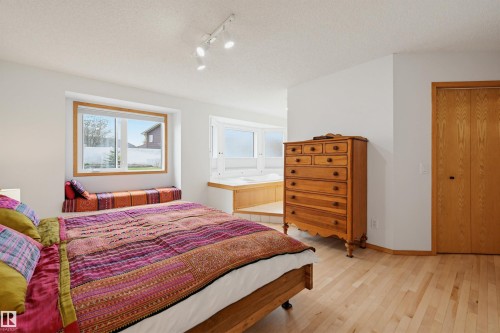 Light wood-finish flooring complements a window with an integrated bench seat - 317 Hollick-Kenyon Road, Edmonton, AB - Indoor Photo Showing Bedroom