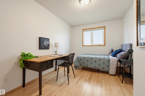 Bright room featuring wood-finish flooring, white walls, and a window with natural wood trim - 317 Hollick-Kenyon Road, Edmonton, AB - Indoor Photo Showing Bedroom