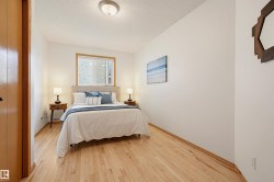 Bedroom featuring light wood-finish flooring, white walls, and a window with a light wood-finish frame - 