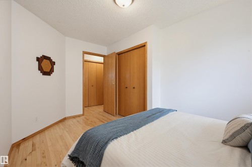 Bedroom featuring light wood-finish flooring, white walls, and wood-paneled closet doors - 317 Hollick-Kenyon Road, Edmonton, AB - Indoor Photo Showing Bedroom