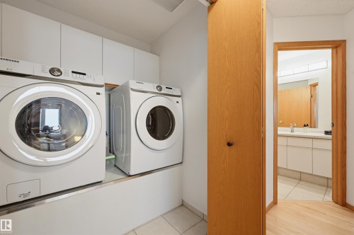 Dedicated laundry area featuring white upper cabinetry, a white platform base, and light-toned tile flooring - 317 Hollick-Kenyon Road, Edmonton, AB - Indoor Photo Showing Laundry Room