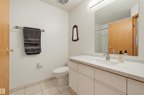 Bathroom featuring a white vanity with an integrated sink, a speckled countertop, and a large wall-mounted mirror - 317 Hollick-Kenyon Road, Edmonton, AB - Indoor Photo Showing Bathroom
