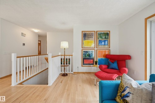 Hardwood flooring throughout the upper level, featuring white wall paint, a built-in staircase with white railing, and wood-trimmed windows - 317 Hollick-Kenyon Road, Edmonton, AB - Indoor
