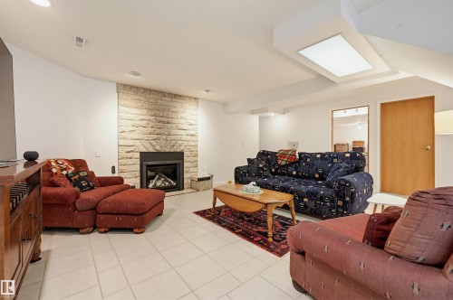 Spacious living area featuring a stone-clad fireplace and light-toned tile flooring - 317 Hollick-Kenyon Road, Edmonton, AB - Indoor Photo Showing Living Room With Fireplace