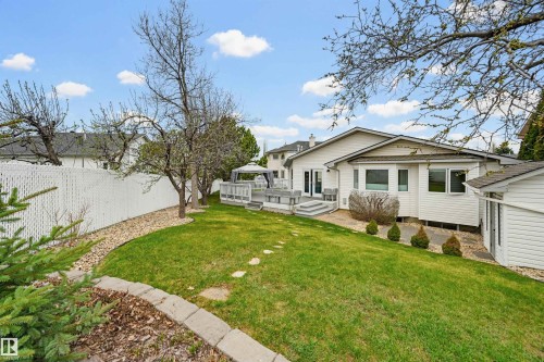 Spacious backyard with a multi-level deck, white vinyl fencing, a detached storage shed, a stone paver path, and mature landscaping - 317 Hollick-Kenyon Road, Edmonton, AB - Outdoor