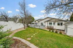 Spacious backyard with a multi-level deck, white vinyl fencing, a detached storage shed, a stone paver path, and mature landscaping - 