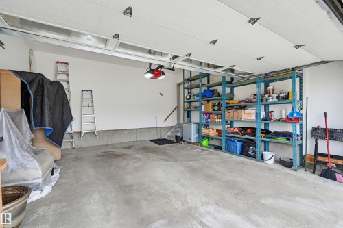 Attached garage with concrete flooring, automatic garage door opener, and extensive built-in shelving - 317 Hollick-Kenyon Road, Edmonton, AB - Indoor Photo Showing Garage