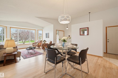 Open-concept living space featuring light wood-finish flooring, a contemporary pendant light fixture, a bay window with a wide sill, and a white paneled entry door - 317 Hollick-Kenyon Road, Edmonton, AB - Indoor Photo Showing Dining Room