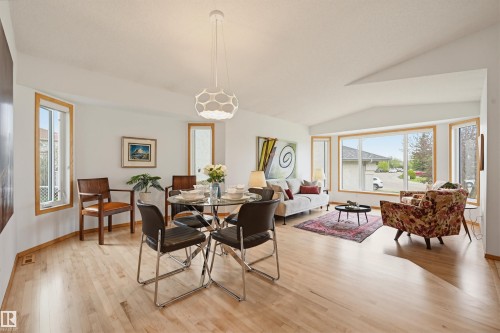Open-concept living space featuring wood-finish flooring, vaulted ceilings, and large bay windows - 317 Hollick-Kenyon Road, Edmonton, AB - Indoor Photo Showing Dining Room