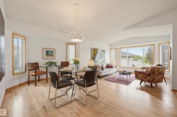Open-concept living space featuring wood-finish flooring, vaulted ceilings, and large bay windows - 