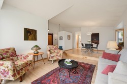 Living area featuring light wood-finish flooring, white walls, and an elevated dining space - 