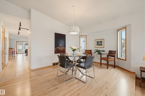 Dining area featuring light wood-finish flooring, a contemporary pendant light fixture, and multiple windows with wood trim - 317 Hollick-Kenyon Road, Edmonton, AB - Indoor Photo Showing Dining Room
