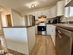 Kitchen featuring white cabinetry, wood-finish flooring, a central island, stainless steel appliances, and a double basin sink - 