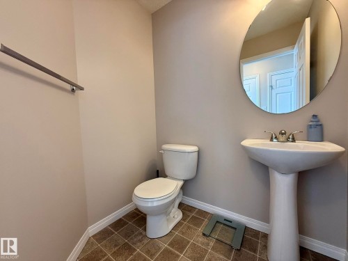 Pedestal sink with chrome fixtures and a round mirror on the main floor by the backdoor! - 645 Windross Crescent, Edmonton, AB 