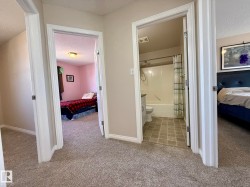 Carpeted hallway with white baseboards and trim, offering access to multiple rooms upstairs! - 