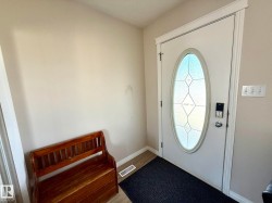 Entry door with an oval-shaped decorative glass insert, complemented by white trim and crown molding - 