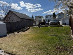 Expansive backyard featuring a sloped lawn and mature perimeter fencing - 