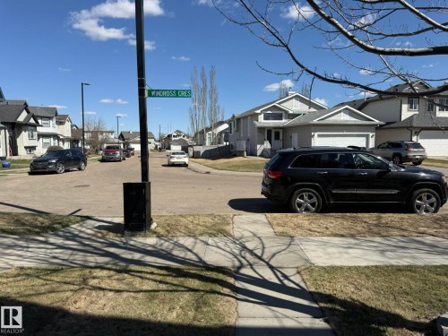 Residential street featuring paved roads and sidewalks, lined with multiple two-story homes - 645 Windross Crescent, Edmonton, AB 