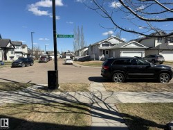 Residential street featuring paved roads and sidewalks, lined with multiple two-story homes - 
