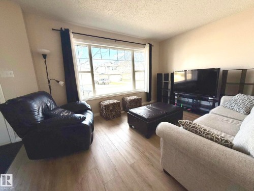 Living area featuring wood-finish flooring, a large window with white trim, and neutral wall tones - 645 Windross Crescent, Edmonton, AB 