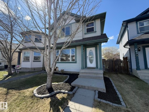 Two-story exterior featuring light-colored siding with Newly PAINTED Dark trim accents, a front entry with an oval glass insert door, and a concrete sidewalk to the front door! - 645 Windross Crescent, Edmonton, AB 
