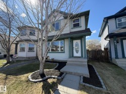 Two-story exterior featuring light-colored siding with Newly PAINTED Dark trim accents, a front entry with an oval glass insert door, and a concrete sidewalk to the front door! - 