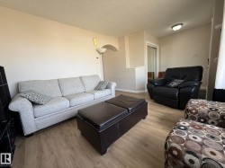 Bright living area featuring wood-finish flooring, neutral-toned walls, and a textured ceiling - 