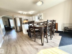 Open-concept kitchen featuring white cabinetry, stainless steel appliances, and a central island with a breakfast bar - 