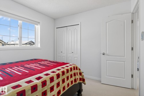 Bright room featuring a large window with white trim, soft neutral carpeting, bi-fold closet doors, and a white interior door - 421 84 Street, Edmonton, AB - Indoor Photo Showing Bedroom
