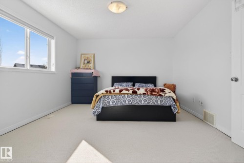 Carpeted room featuring white walls, a large window with white trim, and a white door with a silver knob - 421 84 Street, Edmonton, AB - Indoor Photo Showing Bedroom