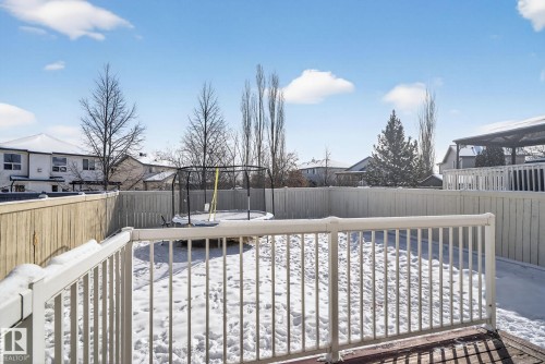 Spacious backyard featuring a wood deck with white railing, fenced perimeter, and mature trees - 421 84 Street, Edmonton, AB - Outdoor With Deck Patio Veranda