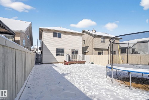 Rear exterior featuring a ground-level wood deck, white vinyl siding, and multiple windows - 421 84 Street, Edmonton, AB - Outdoor