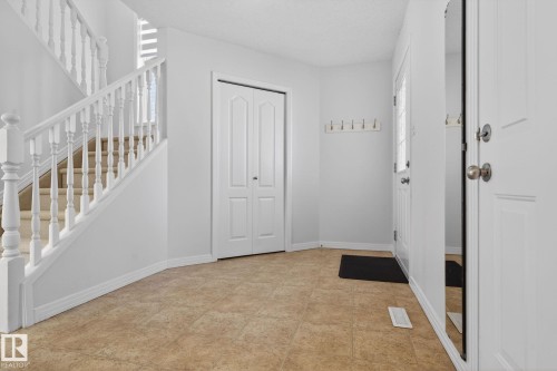 Foyer featuring neutral tile flooring, a carpeted staircase with white balusters, a bi-fold closet door, and a white entry door with frosted glass - 421 84 Street, Edmonton, AB - Indoor Photo Showing Other Room