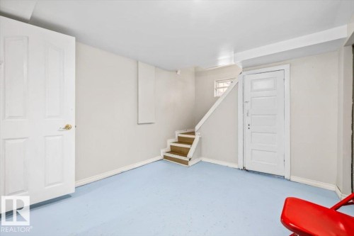 Interior space featuring light blue floor, white walls, and a white paneled door with brass hardware - 10939 96 Street, Edmonton, AB - Indoor Photo Showing Other Room