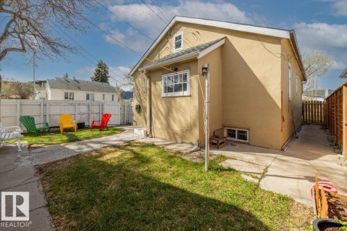 Enclosed backyard featuring a manicured lawn, concrete patio, and white privacy fencing - 10939 96 Street, Edmonton, AB - Outdoor