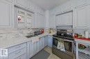Kitchen featuring light-toned cabinetry with metal hardware, a subway tile backsplash, and a stainless steel electric range - 10939 96 Street, Edmonton, AB  - Indoor Photo Showing Kitchen 