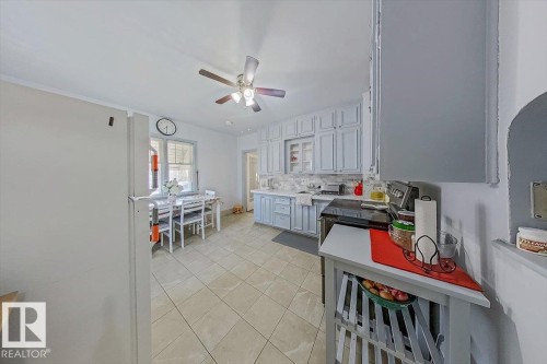 Kitchen featuring light-toned floor tiling, painted cabinetry with a tile backsplash, and a built-in oven - 10939 96 Street, Edmonton, AB - Indoor Photo Showing Other Room