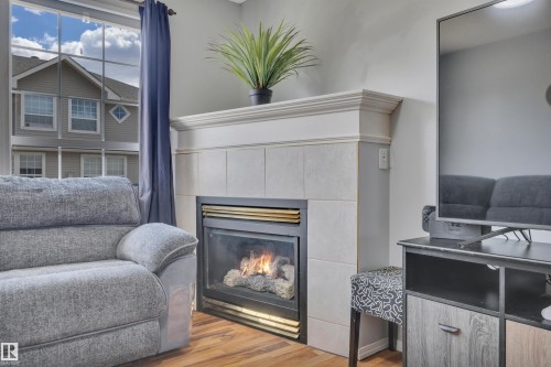 Fireplace featuring a tile surround, decorative mantel, and built-in gas logs - 102 4415 South Park Drive, Leduc, AB - Indoor Photo Showing Living Room With Fireplace
